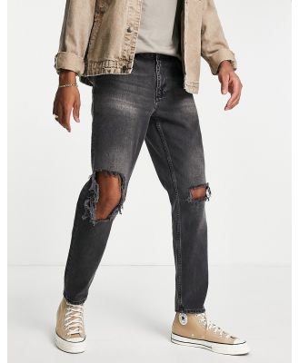 ASOS DESIGN tapered jeans in black wash with busted knee rips